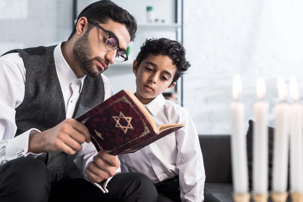Jewish man in glasses reading with a child.